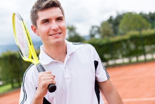 A man with a tennis racket getting ready to play tennis at the tennis court